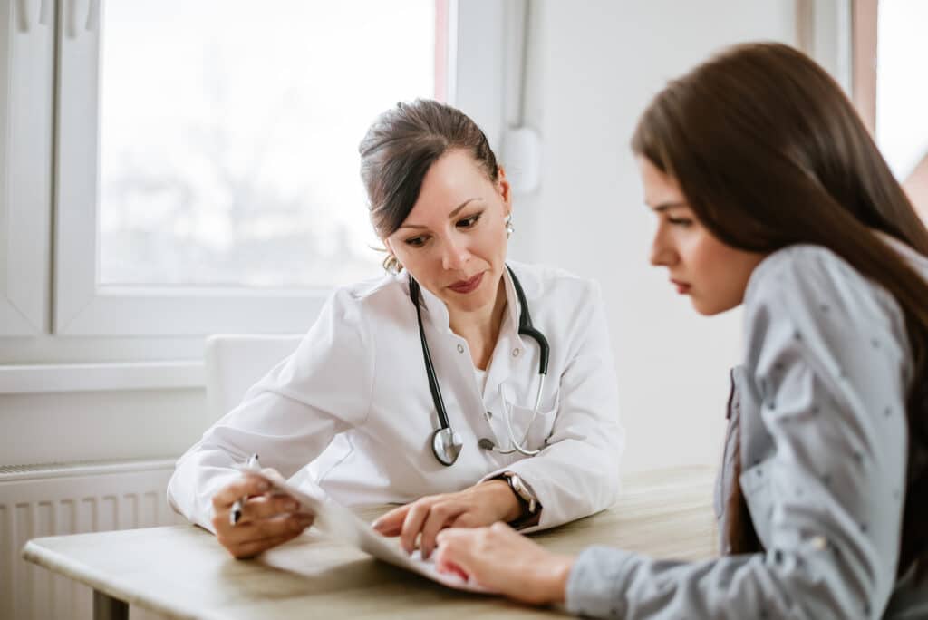 Doctor sitting at a desk, giving advice to a patient. Both the doctor and the patient are women. 